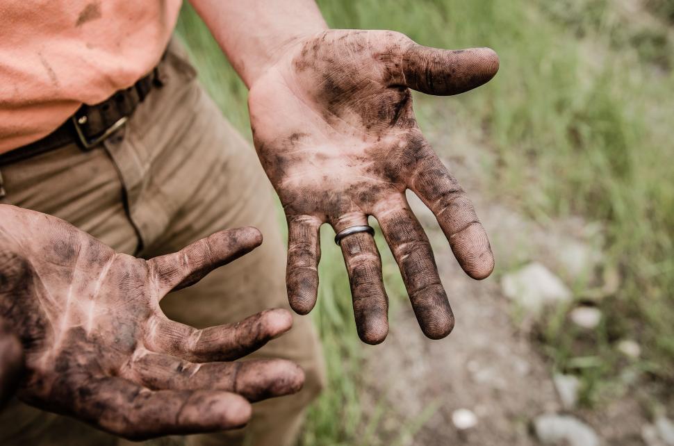 Free Image of Man Holding Out His Mud-Covered Hands 