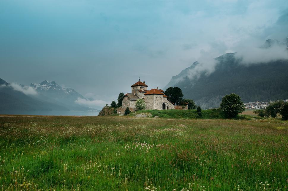 Free Image of Old Church Standing in Field With Mountains 