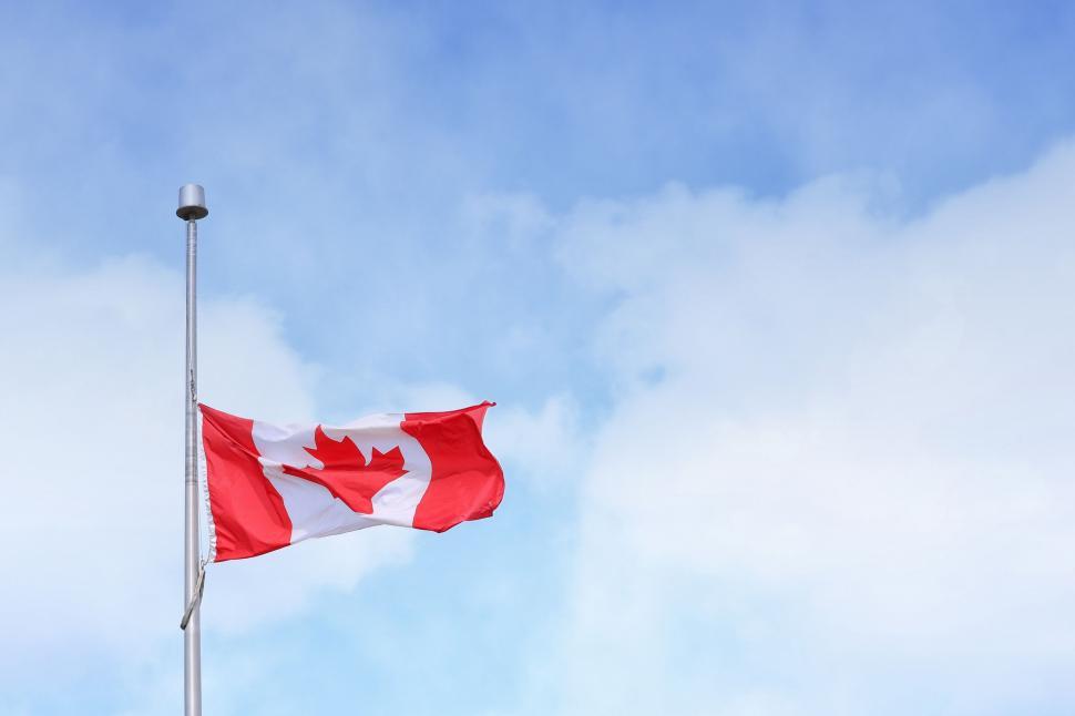 Free Image of Canadian Flag Flying in the Wind on a Cloudy Day 