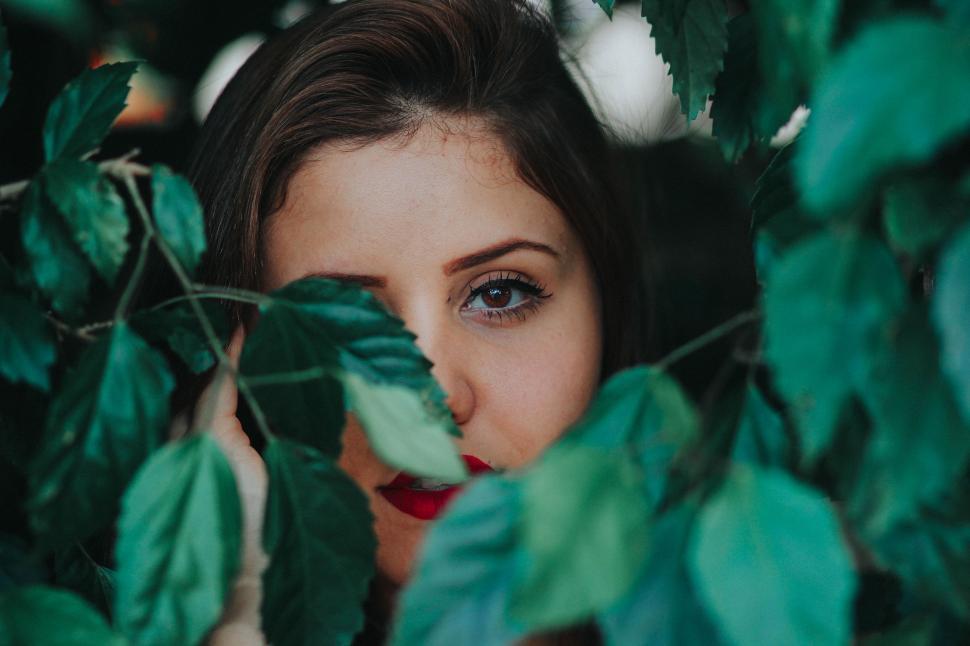 Free Image of Woman Peeking Out From Behind Leaves 
