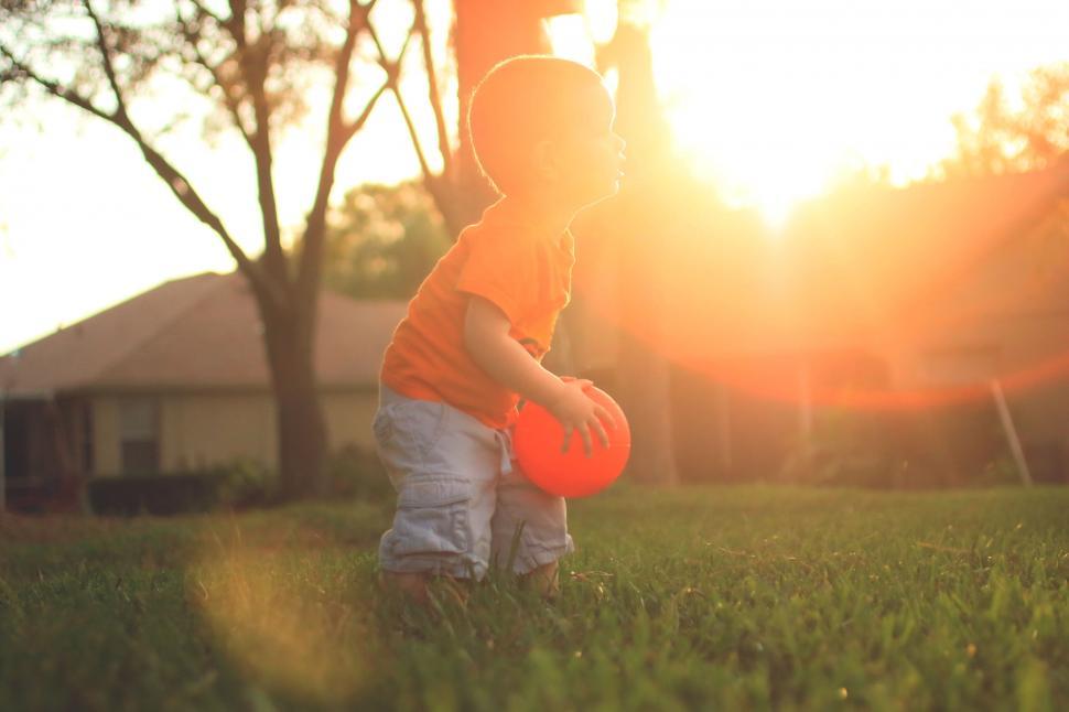 Free Image of Small Child Holding Red Frisbee in Field 
