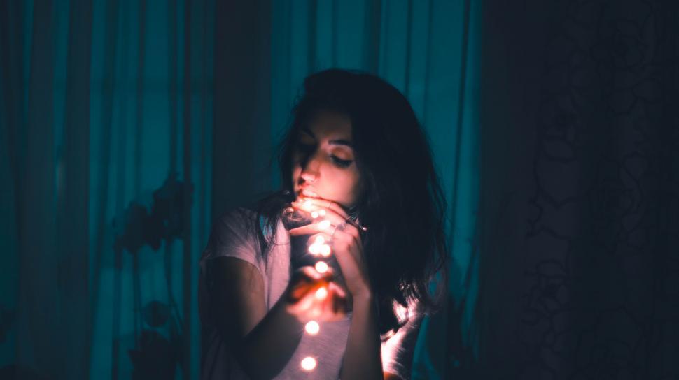 Free Image of Woman Holding Lit Candle in Front of Curtain 