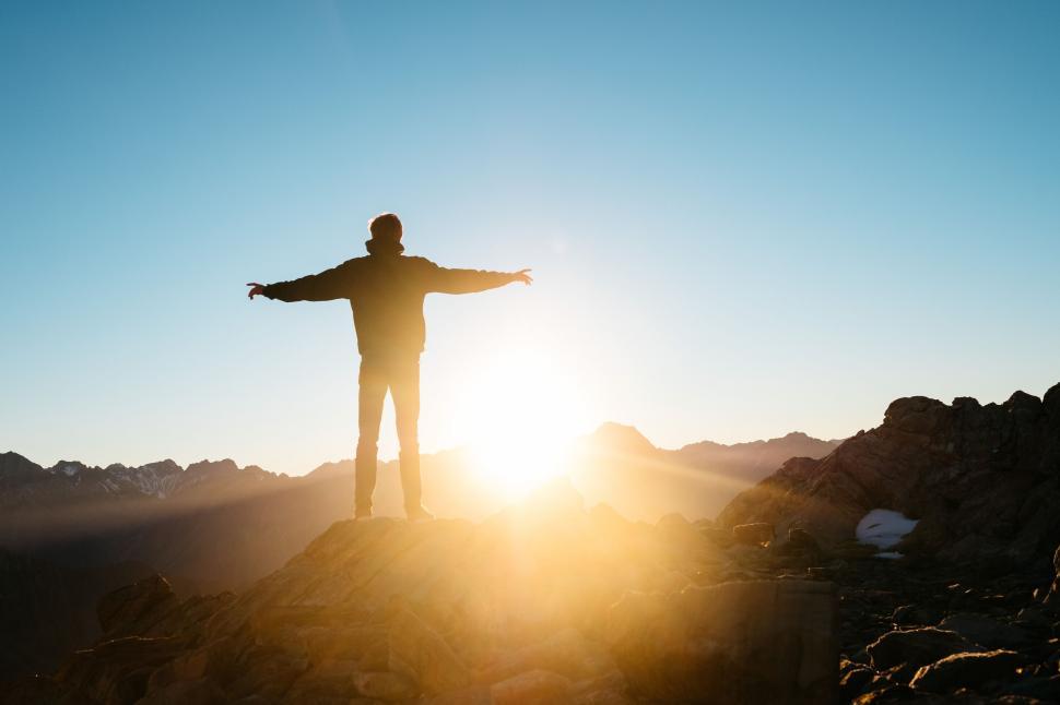 Free Image of Man Standing On Top Of Mountain With Arms Outstretched 