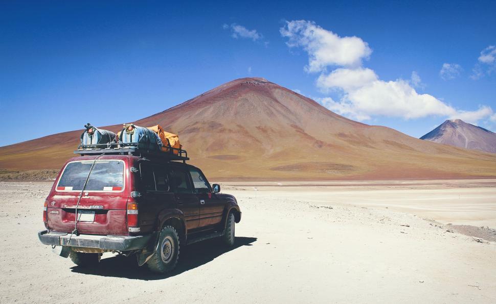 Free Image of Red Van With Luggage on Top in the Desert 