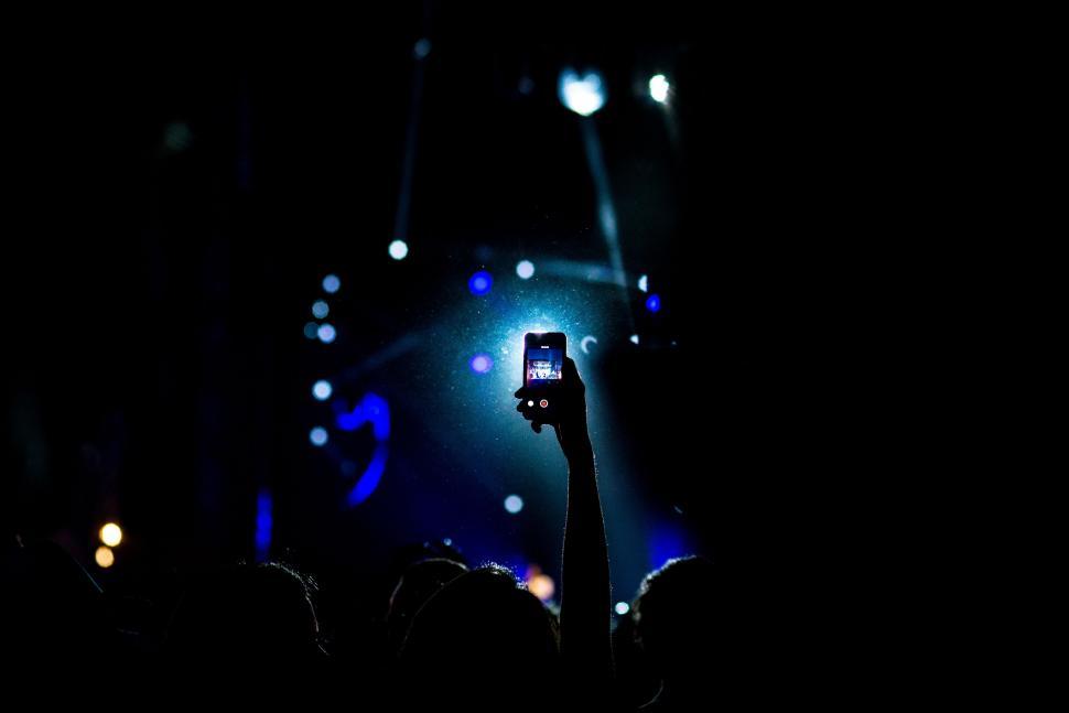 Free Image of Person Holding Up Cell Phone in the Dark 