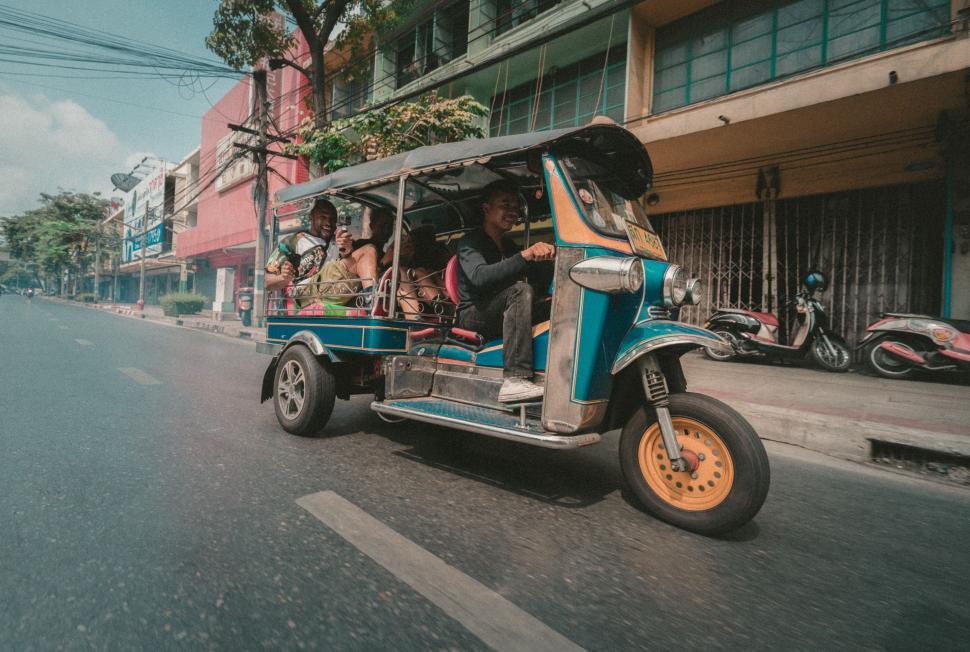 Free Image of Blue and Yellow Tuk Tuk Driving Down a Street 