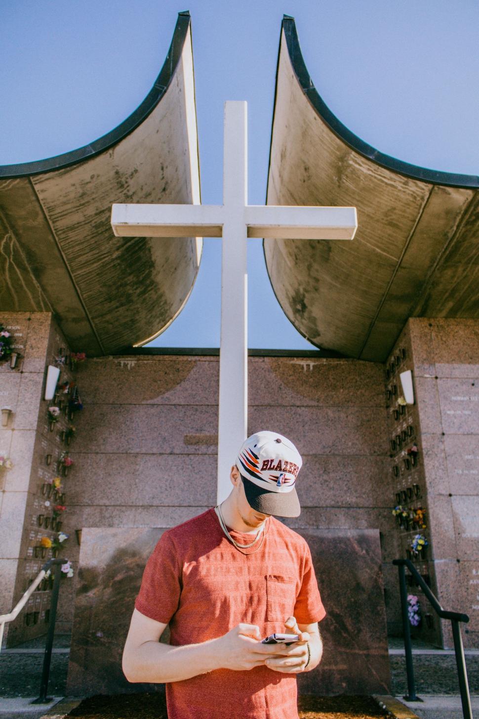Free Image of Man Standing in Front of Large Cross 