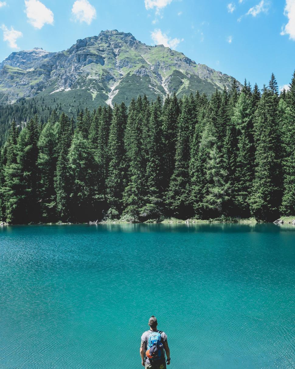 Free Image of Man Standing on Edge of Lake With Mountain in Background 