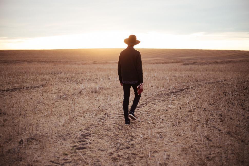 Free Image of Man Walking Across Field With Hat On 