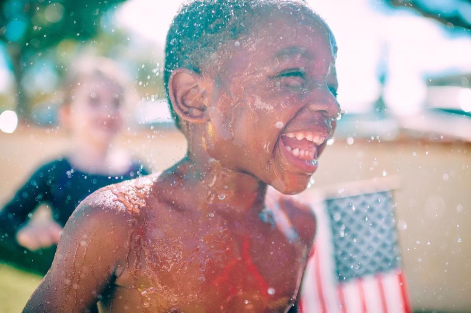 Free Image of Young Boy Playing in Water With American Flag 