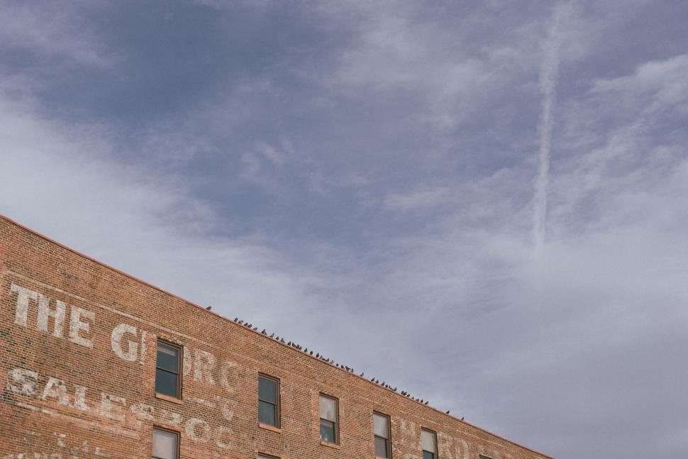 Free Image of Old Building With Plane Flying in the Sky 