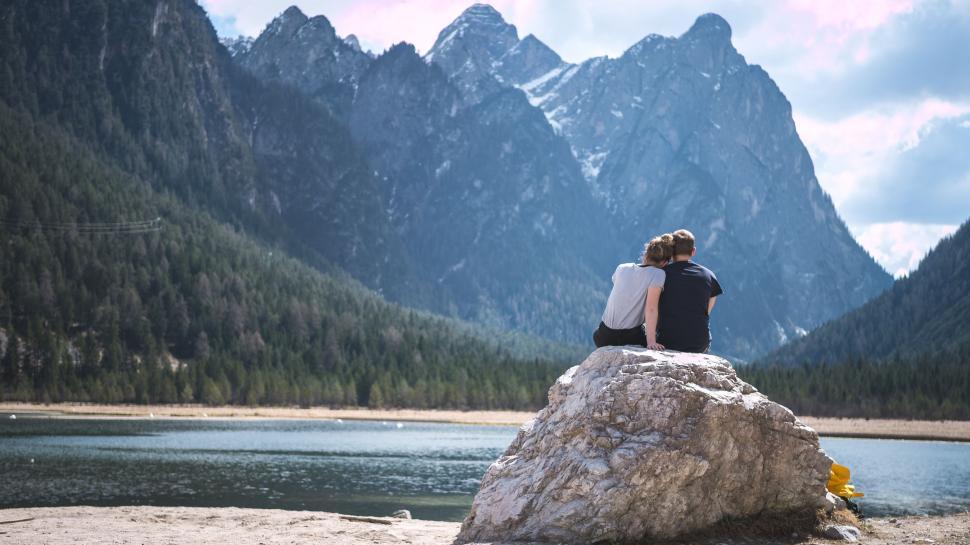 Free Image of Couple Sitting on Rock Overlooking Mountain Lake 