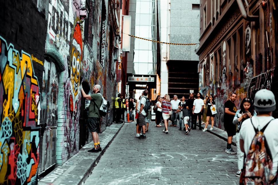 Free Image of Group of People Walking Down Street Next to Tall Buildings 