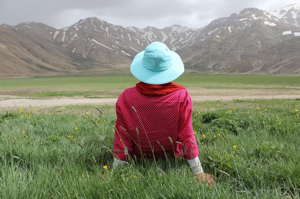 Free Image of Person Sitting in Field With Mountains in Background 
