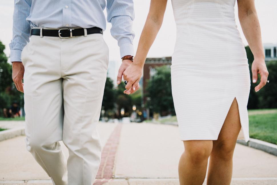 Free Image of Man and Woman Walking Down Sidewalk Holding Hands 