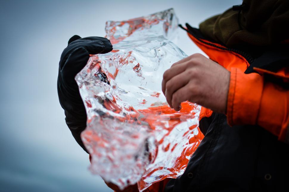 Free Image of Person in an Orange Jacket Holding a Piece of Foil 