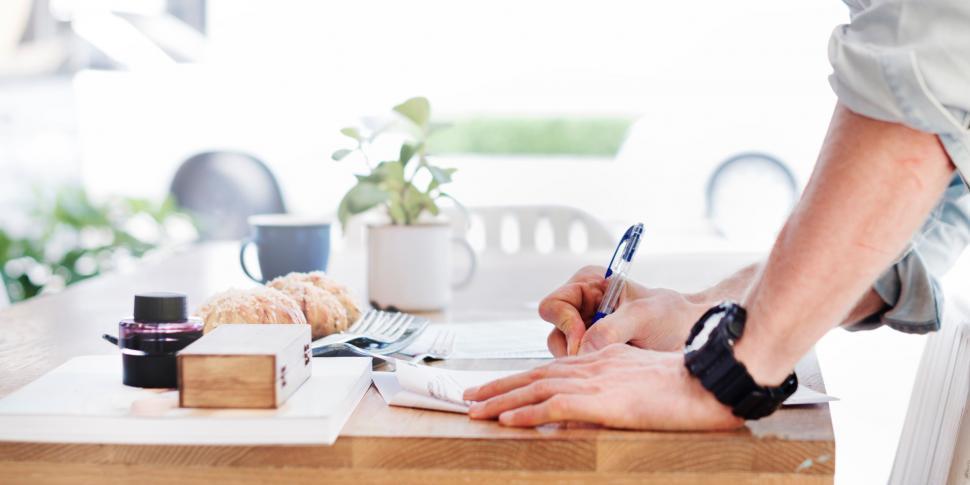 Free Image of Person Writing on a Piece of Paper on a Table 