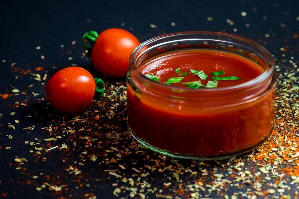 Free Image of Jar of Tomato Sauce Next to Two Tomatoes 