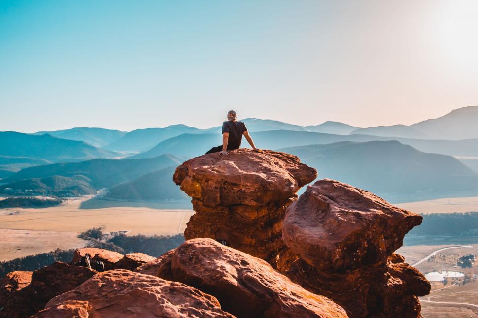 Free Image of Person Sitting on Top of a Large Rock 