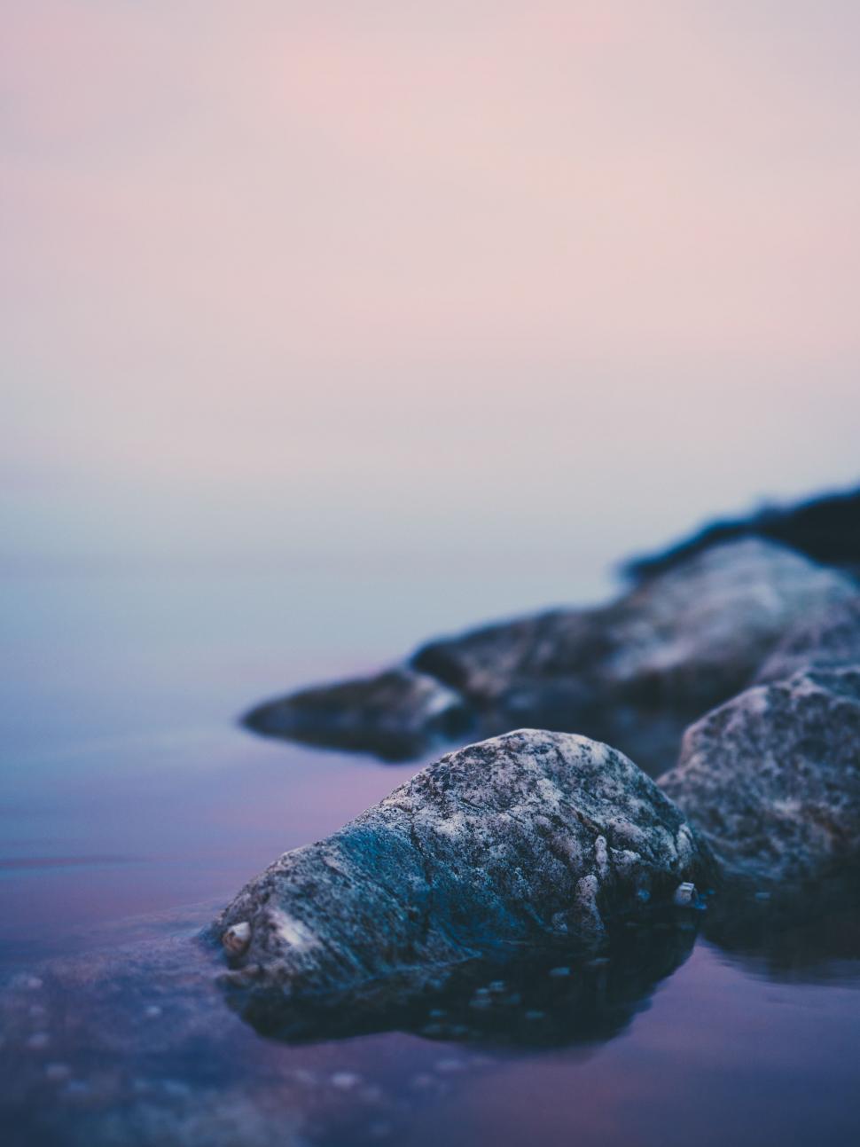 Free Image of Blurry Photo of Rocks, Water, and Building 