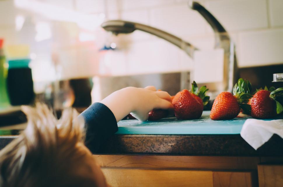 Free Image of Young Boy Cutting Strawberries on Cutting Board 