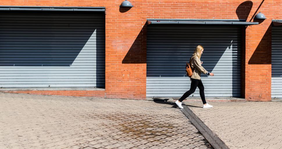 Free Image of Woman Walking Past Garage Doors 