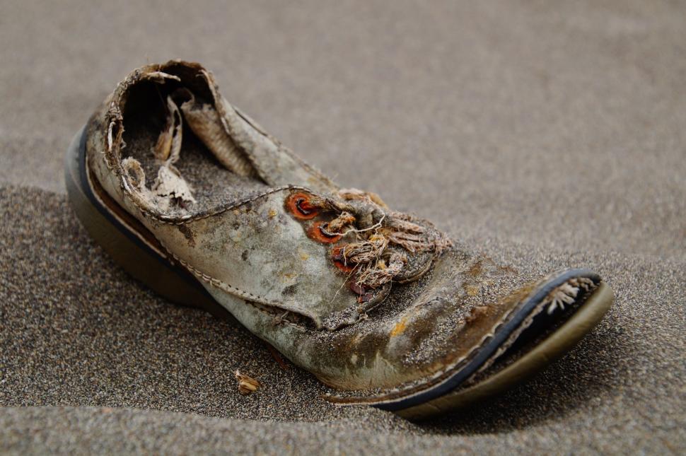 Free Image of Worn Out Shoe Resting on Sandy Beach 
