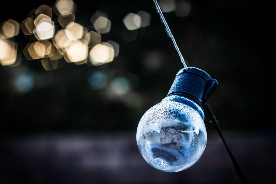 Free Image of Light Bulb Hanging From Wire Against Blurry Background 